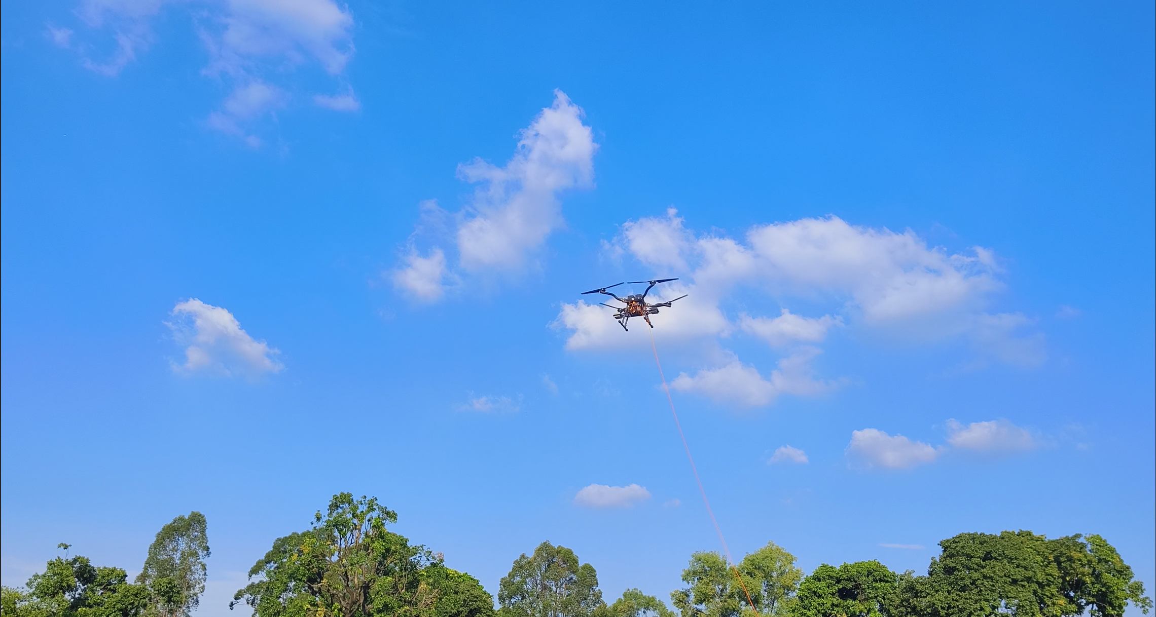 XJ-XLA tethered drone in flight above trees.